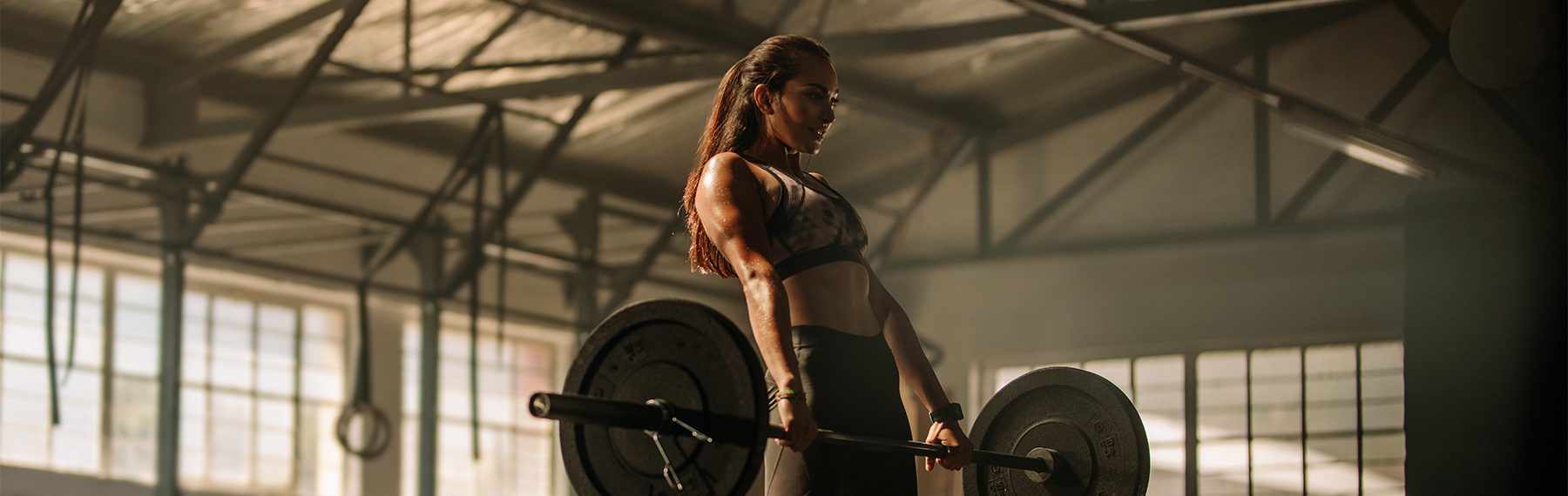 Strong female athlete holding a barbell in her hands. gym woman lifting heavy weights in gym.