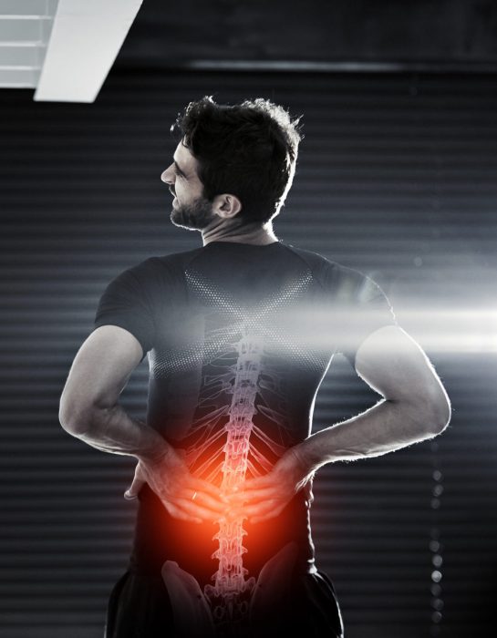 Rearview shot of a man holding his injured back after a workout